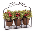 Three artificial green plants with red berries displayed in a decorative metal caddy